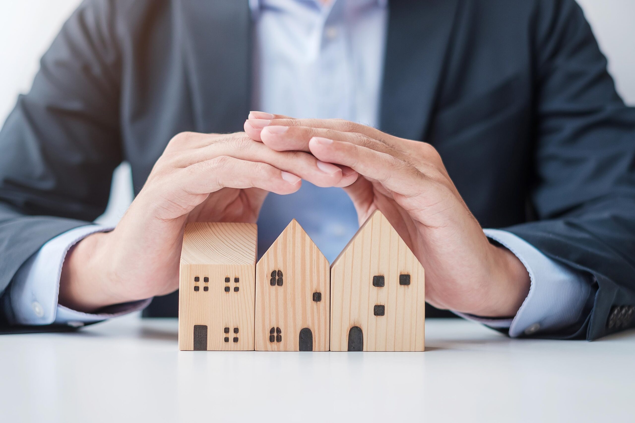 Businessman hand cover wooden Home model. real estate, insurance and property concepts