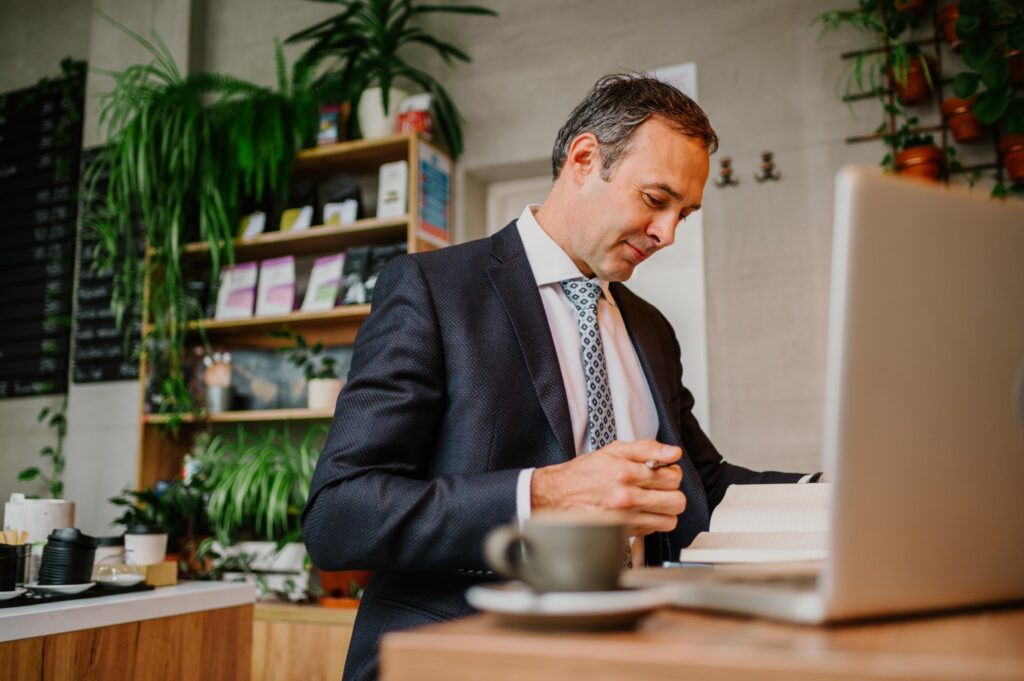 Man Working in Cafe with Laptop and Planner